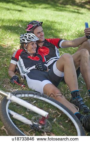 Stock Photograph - Cyclists on grass taking selfie. Fotosearch