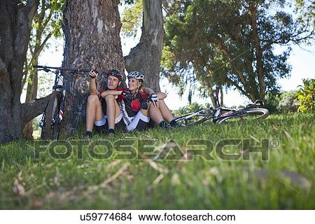 Cyclists resting by tree View Large Photo Image Picture - Cyclists resting by tree. Fotosearch