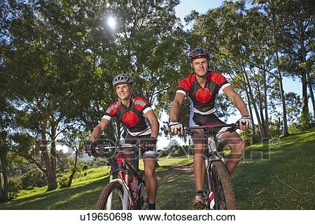 Stock Photo - Cyclists riding bicycle in park. Fotosearch