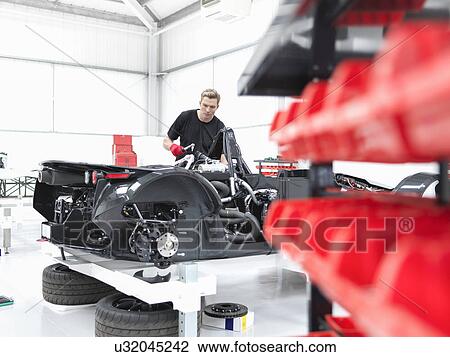 Stock Image - Engineer assembling supercar in sports car factory. Fotosearch