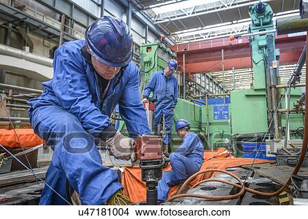 Picture - Engineer drilling during power station outage. Fotosearch