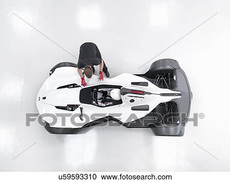 Stock Image - Engineer in discussion with racing driver in supercar, overhead view. Fotosearch