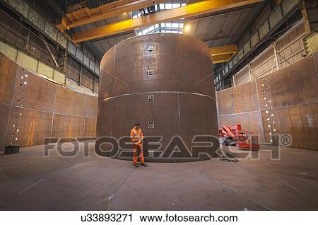 Stock Image - Engineer inspecting marine fabrication used for cable laying. Fotosearch