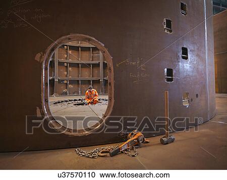Stock Image - Engineer inspecting marine fabrication used for cable laying. Fotosearch