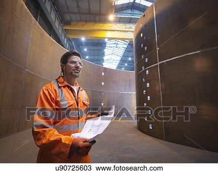 Stock Image - Engineer inspecting marine fabrication used for cable laying. Fotosearch