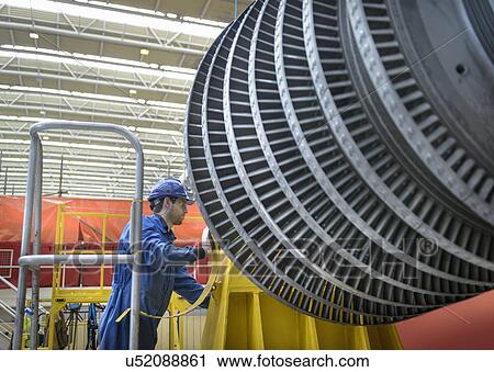 Stock Image - Engineer inspecting turbine during power station outage. Fotosearch