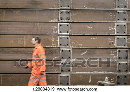 Stock Photo - Engineer walking past marine fabrication in factory. Fotosearch