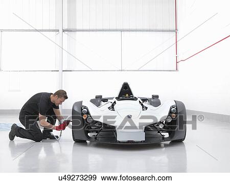 Stock Photo - Engineer working with supercar in factory. Fotosearch