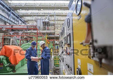 Stock Image - Engineers discussing paperwork during power station outage. Fotosearch