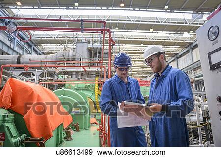 Stock Photo - Engineers discussing paperwork during power station outage. Fotosearch
