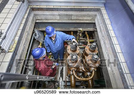 Stock Photo -  Engineers inspecting electrical unit during power station outage, elevated view. Fotosearch