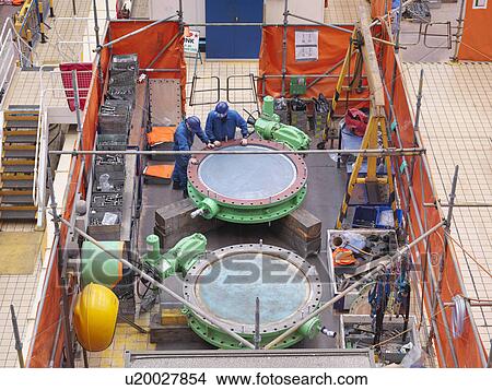 Engineers repairing flange valves during power station outage, high angle view View Large Photo Image Picture - Engineers repairing flange valves during power station outage, high angle view. Fotosearch