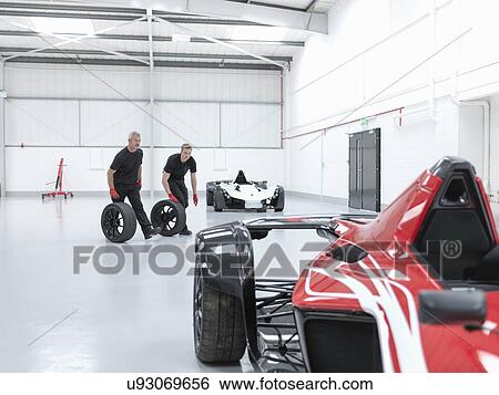 Engineers rolling wheels near supercar in sports car factory View Large Photo Image Stock Photograph - Engineers rolling wheels near supercar in sports car factory. Fotosearch