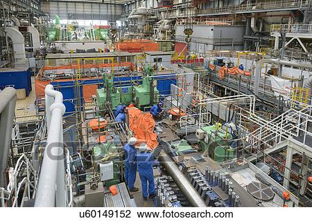 Stock Image - Engineers working on turbine housing repair during power station outage, high angle view. Fotosearch