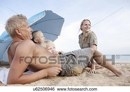 Family with two children relaxing on beach View Large Photo Image Stock Photograph - Family with two children relaxing on beach. Fotosearch