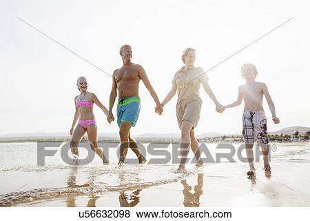 Family with two children strolling and holding hands on beach View Large Photo Image Stock Photo - Family with two children strolling and holding hands on beach. Fotosearch