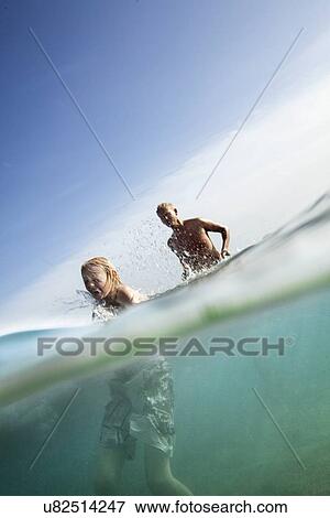 Stock Photo - Father with son splashing and wading through sea. Fotosearch