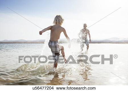 Father with son splashing each other on beach View Large Photo Image Picture - Father with son splashing each other on beach. Fotosearch