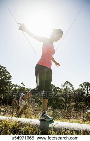 Female jogger balancing on pipe View Large Photo Image Stock Photography - Female jogger balancing on pipe. Fotosearch