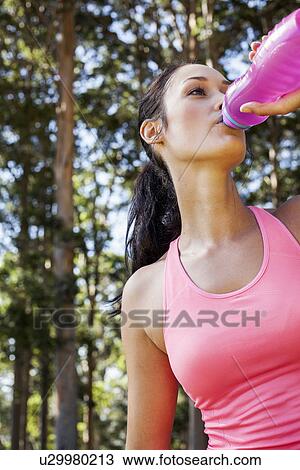 Stock Image - Female jogger drinking from water bottle. Fotosearch