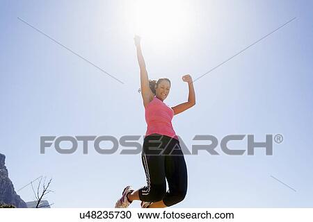 Stock Image - Female jogger jumping in mid air. Fotosearch