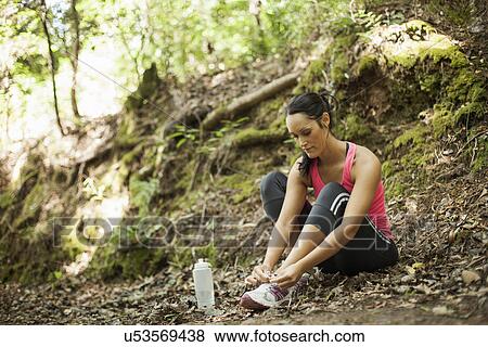 Female jogger tying shoelace in forest View Large Photo Image Stock Photo - Female jogger tying shoelace in forest. Fotosearch