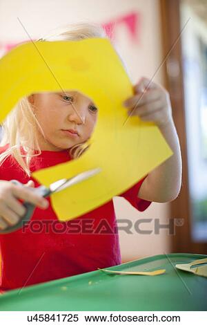 Stock Photography - Girl cutting out cardboard shapes at nursery school. Fotosearch