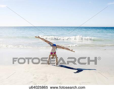 Stock Photography - Girl doing handstand and splits on beach. Fotosearch