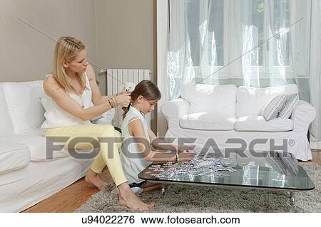Girl doing jigsaw whilst mother plaits her hair View Large Photo Image Stock Photograph - Girl doing jigsaw whilst mother plaits her hair. Fotosearch