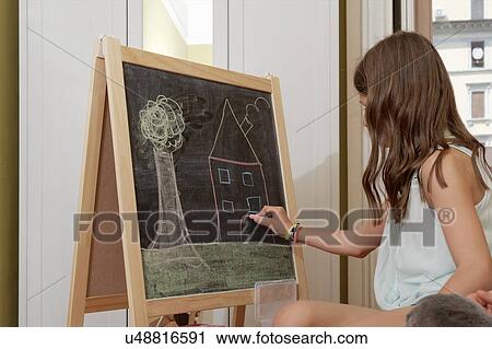 Stock Image - Girl drawing on blackboard. Fotosearch