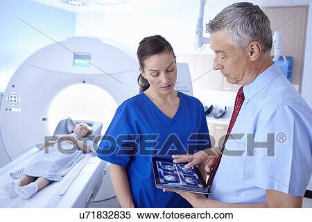 Stock Photography - Girl in CT scanner, doctor and radiographer looking at scan on digital tablet. Fotosearch