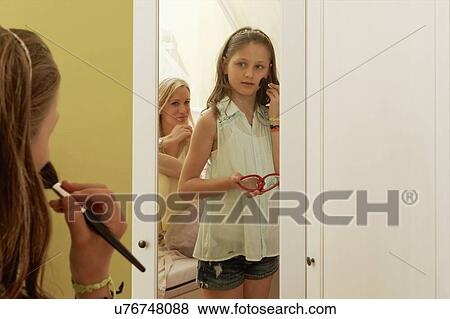 Girl putting on blusher in mirror whilst mother watches View Large Photo Image Stock Photo - Girl putting on blusher in mirror whilst mother watches. Fotosearch