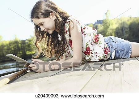 Girl using digital tablet on jetty View Large Photo Image Stock Image - Girl using digital tablet on jetty. Fotosearch