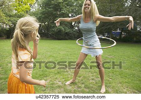 Stock Photography - Girl watching mother hula hooping. Fotosearch