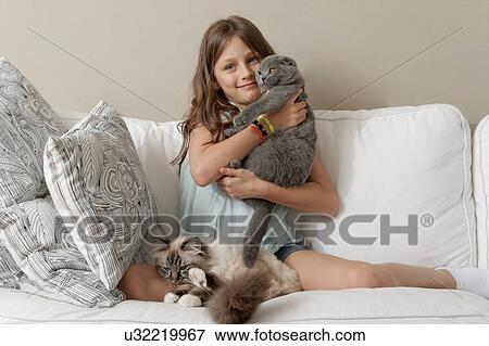 Girl with two cats on sitting room sofa View Large Photo Image Stock Photo - Girl with two cats on sitting room sofa. Fotosearch
