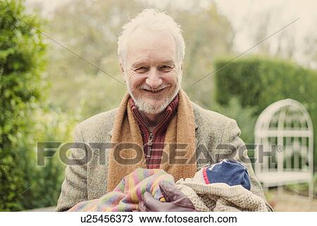 Stock Image - Grandfather cradling grandson, portrait. Fotosearch