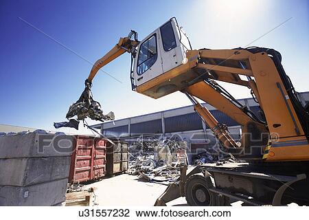 Stock Image - Grapple handler sorting and moving metals in scrap yard. Fotosearch
