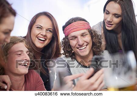 Group of five young adult friends looking at smartphone View Large Photo Image Stock Photograph - Group of five young adult friends looking at smartphone. Fotosearch