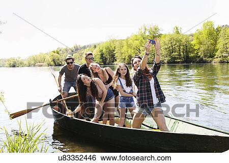 Stock Photograph - Group of friends in a row boat taking photo of themselves. Fotosearch