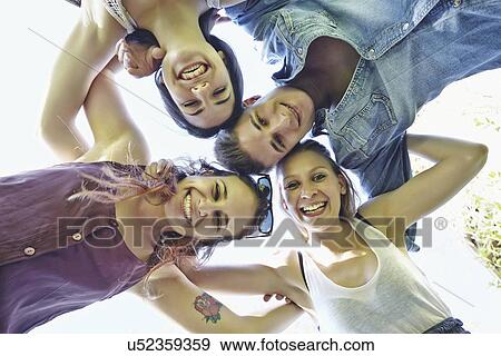 Group of friends in huddle smiling, low angle View Large Photo Image Stock Photo - Group of friends in huddle smiling, low angle. Fotosearch