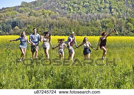 Picture - Group of friends running in field. Fotosearch