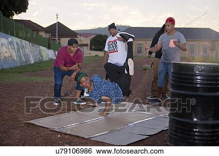 Stock Photograph - Group of men breakdancing in park at dusk. Fotosearch