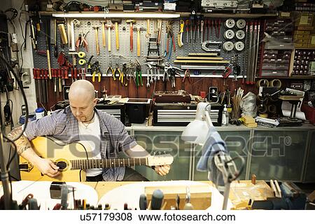 Guitar maker tuning acoustic guitar in workshop View Large Photo Image Stock Photo - Guitar maker tuning acoustic guitar in workshop. Fotosearch
