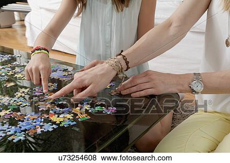 Hands of mother and daughter doing jigsaw puzzle View Large Photo Image Stock Photo - Hands of mother and daughter doing jigsaw puzzle. Fotosearch