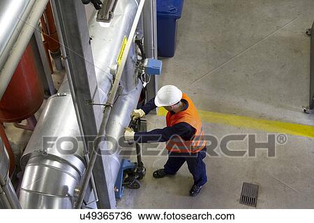 Stock Photograph - High angle view of technician with pallet trolley in power station. Fotosearch