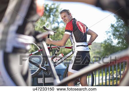 Male cyclist carrying bicycle View Large Photo Image Stock Image - Male cyclist carrying bicycle. Fotosearch