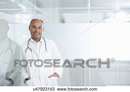 Male doctor leaning against reflective wall View Large Photo Image Stock Image - Male doctor leaning against reflective wall. Fotosearch