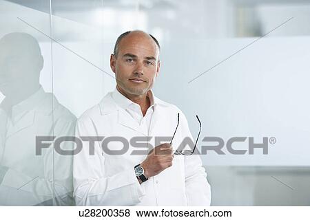 Stock Photo - Male doctor leaning against reflective wall. Fotosearch