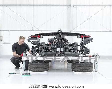 Stock Photo - Male engineer assembling supercar in sports car factory. Fotosearch