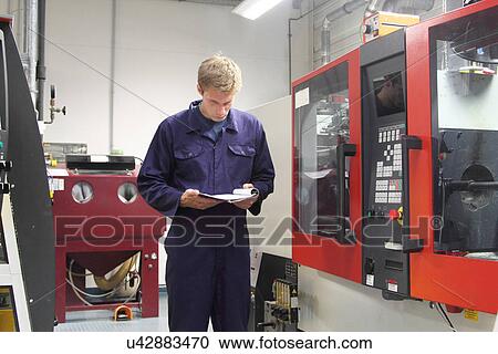 Male engineer checking machinery paperwork in factory View Large Photo Image Stock Image - Male engineer checking machinery paperwork in factory. Fotosearch